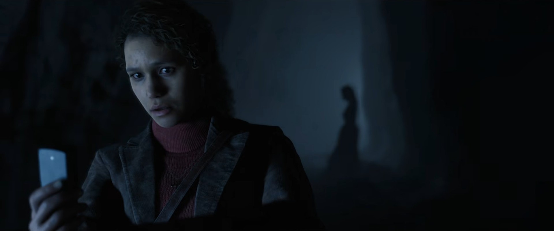 The Conjuring: Unspoken – Francesca Noakes hält ihr Smartphone in einem dunklen Flur